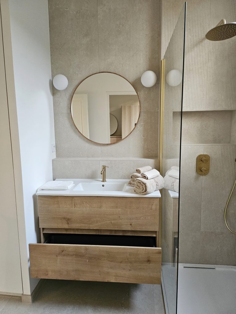 renovation salle de bain avec meuble vasque bois et robinet laiton et carrelage travertin