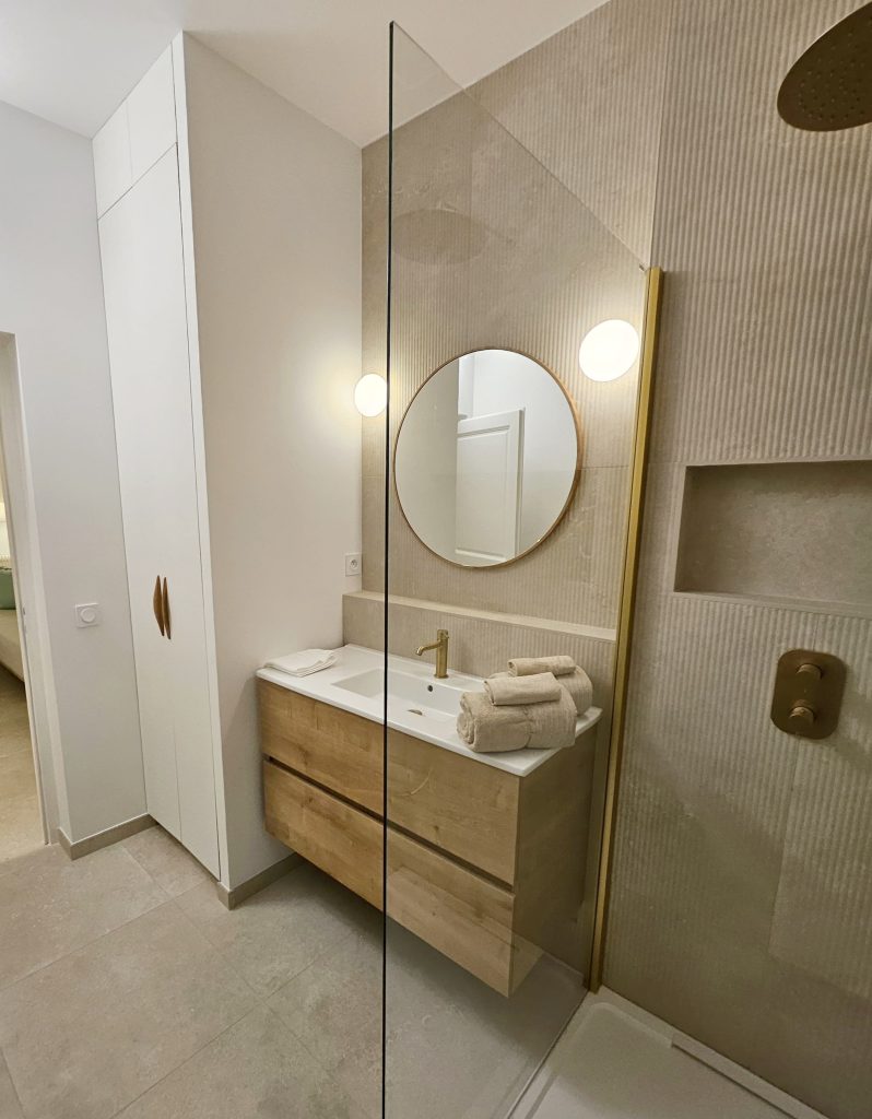 renovation et décoration salle de bain avec carrelage cannelé travertin et robinetterie laiton et son placard sur mesure buanderie